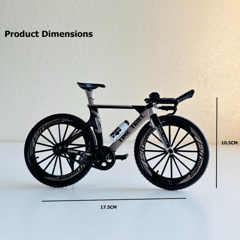 May include: Black and white toy bicycle model with the words "Time Trial" printed on the frame. The bicycle is 17.5 inches long and 10.5 inches tall.