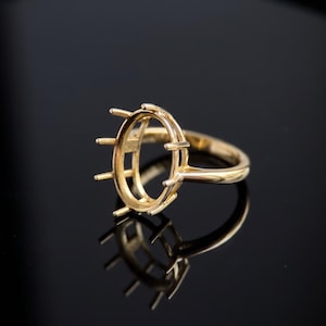 May include: A gold ring setting featuring an oval-shaped head with six prongs designed to hold a gemstone. The band is smooth and polished, showcasing a classic metal construction intended for jewelry assembly and custom ring creation.