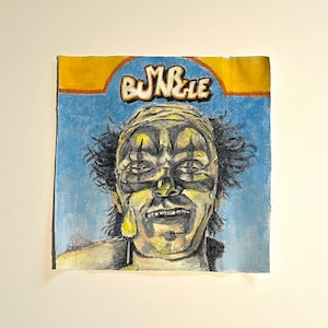 May include: A hand-painted illustration of a clown with a yellow and green face, black hair, and a blue background. The text "BUNDLE" is written in yellow letters above the clown's head.