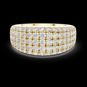 May include: A wide, gold-toned ring encrusted with multiple rows of sparkling, clear gemstones. The ring has a rounded shape and a polished finish, reflecting light against a dark background. The gemstones are evenly spaced, creating a dazzling effect.