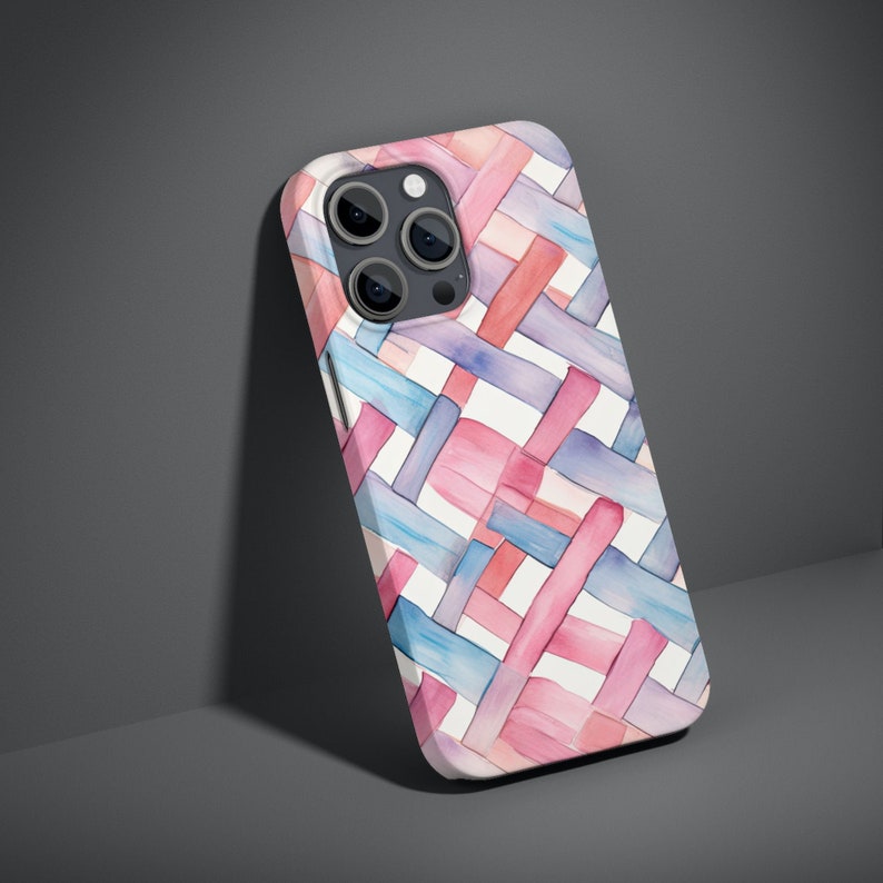 May include: A white phone case with a geometric pattern of pink and blue watercolor stripes. The case is designed for a phone with a triple camera lens.