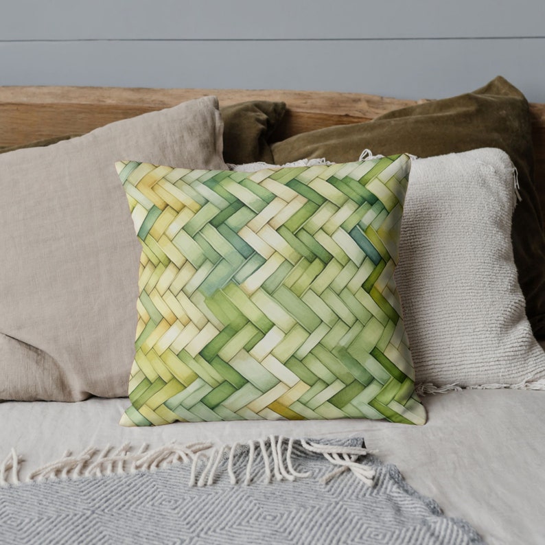 May include: A green and yellow woven pillow with a geometric pattern. The pillow is on a bed with other pillows and a blanket.
