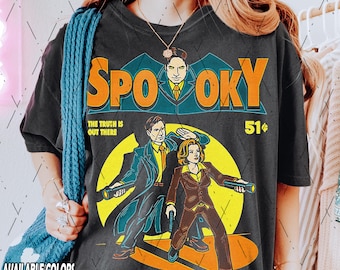 May include: A black t-shirt with a vintage comic book style graphic of two people holding flashlights. The graphic says "Spooky" and "The truth is out there" with a price of 51 cents.
