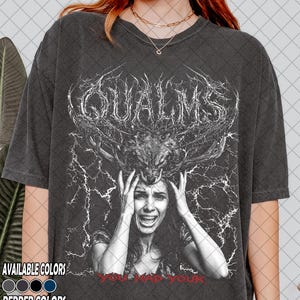 Puede incluir: Una camiseta gris carbón de manga corta con un estampado gráfico blanco de una persona con las manos en la cabeza, coronada por un cráneo de ciervo. Sobre la figura aparece el texto QUALMS en fuente irregular y debajo el texto YOU HAD YOUR.