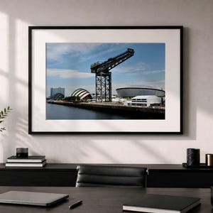 Peut inclure: Une photographie de paysage encadrée montrant la grue Finnieston le long de la rivière Clyde à Glasgow, en Écosse, avec les bâtiments SEC Armadillo et OVO Hydro visibles en arrière-plan sous un ciel bleu clair parsemé de quelques nuages.