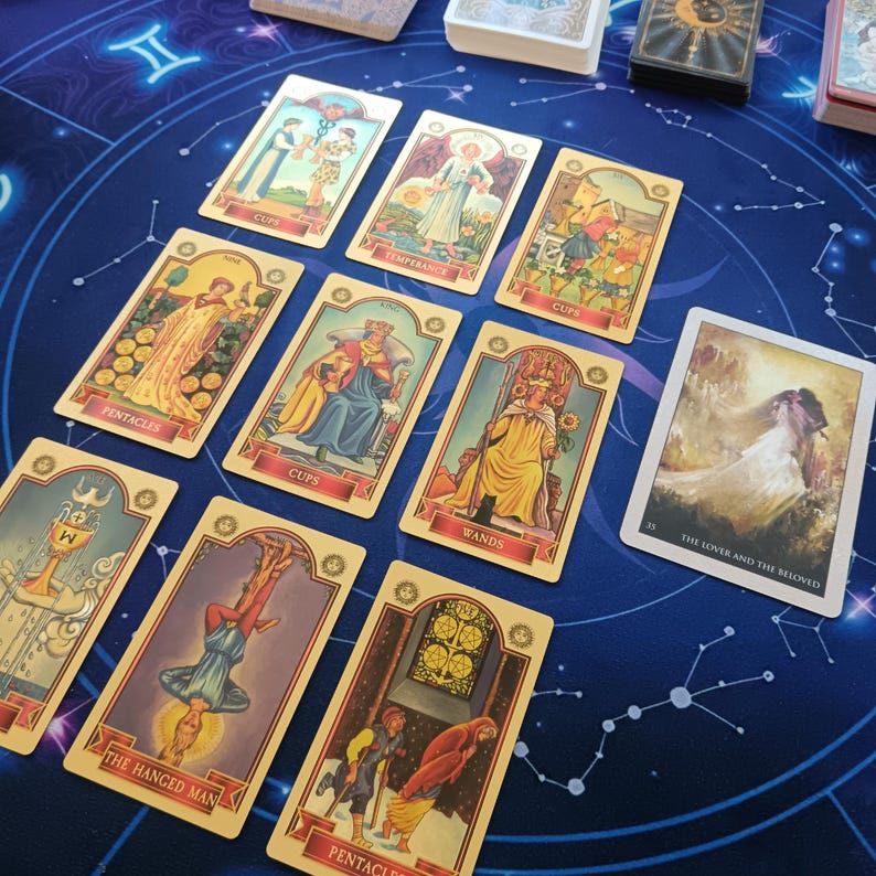 a collection of tarot cards spread out on a blue background with a starry night sky pattern.