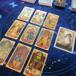 a collection of tarot cards spread out on a blue background with a starry pattern.