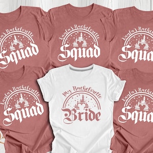 May include: Five pink t-shirts with white text and a graphic of a castle. The text on four of the shirts reads "Kayla's Bachelorette Squad". The text on the fifth shirt reads "My Bachelorette Bride".