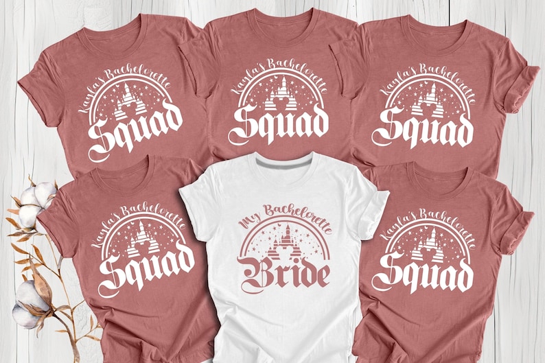 May include: Five pink t-shirts with white text and a graphic of a castle. The text on four of the shirts reads "Kayla's Bachelorette Squad". The text on the fifth shirt reads "My Bachelorette Bride".