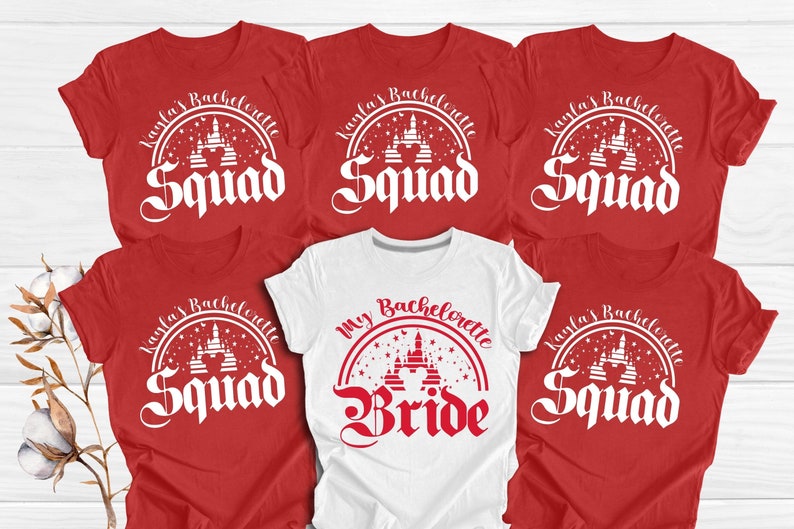 May include: Six red t-shirts with white text and a white graphic of a castle. One white t-shirt with red text and a red graphic of a castle. The text on the red shirts says "Kayla's Bachelorette Squad". The text on the white shirt says "My Bachelorette Bride".