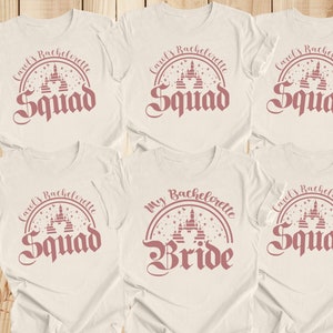 May include: Six white t-shirts with pink text and a pink graphic of a castle. The text on the shirts reads "Carol's Bachelorette Squad" and "My Bachelorette Bride".