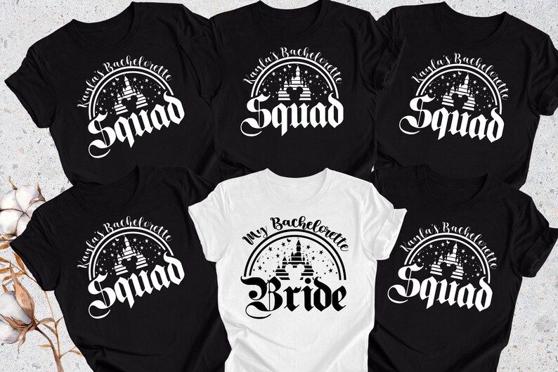 May include: Five black t-shirts with white text and a graphic of a castle. One white t-shirt with black text and a graphic of a castle. The text on the black shirts reads "Kayla's Bachelorette Squad". The text on the white shirt reads "My Bachelorette Bride".