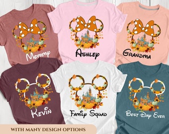 Puede incluir: Cinco camisetas con diferentes diseños que presentan una cabeza de Mickey Mouse de dibujos animados con una corona de otoño y una silueta del castillo de Cenicienta. Las camisetas tienen el texto "Mommy", "Ashley", "Grandma", "Kevin" y "Family Squad" en ellas. La última camiseta tiene el texto "Best Day Ever" en ella.