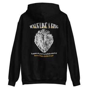 Könnte beinhalten: Schwarzer Hoodie mit einem weißen Löwenkopf-Motiv und dem Text "Walk Like A King" in goldenen Buchstaben. Der Text "Sammu ni parva jehda marzi hove Raja dekh la ge" ist ebenfalls in goldenen Buchstaben unter dem Löwen aufgedruckt.