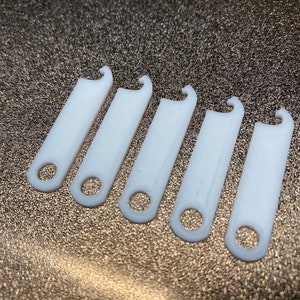 May include: Six white plastic hooks with a rounded opening at the bottom and a hook at the top.