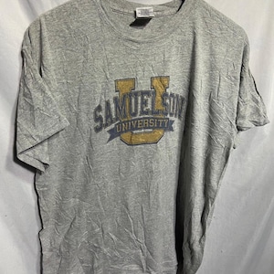 May include: A gray t-shirt with a blue and yellow graphic of the text "Samuelson University" with a large "U" in the center.