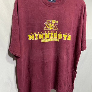 May include: A maroon t-shirt featuring a gold University of Minnesota logo. The logo depicts the school's mascot, the Golden Gopher, and the words "University of Minnesota" and "Golden Gophers".