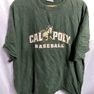 Puede incluir: Camiseta verde con un gráfico dorado y blanco de un caballo corriendo y el texto "Cal Poly Baseball".