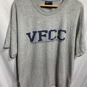 May include: Gray t-shirt with the text "VFCC Valley Forge Christian College" printed in navy blue.