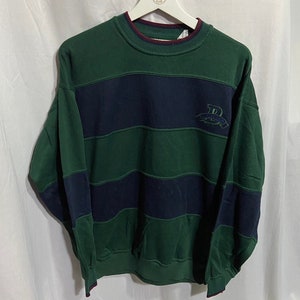 May include: Green and navy blue striped sweatshirt with a red trim around the neck and cuffs. The sweatshirt has a small embroidered logo on the front that says "Burlington".