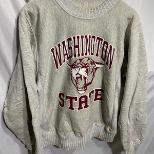 May include: A grey sweatshirt with a maroon Washington State Cougars logo. The logo features a cougar head with the words "Washington" and "State" in a maroon arch.