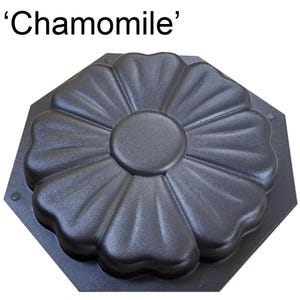 May include: Black, flower-shaped mold with the word 'Chamomile' at the top. The mold has a textured surface and a central circular area surrounded by petal-like shapes. The base is an octagon.