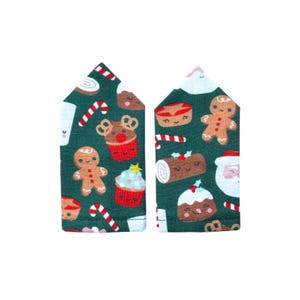 May include: Two fabric pieces with a dark green background and a repeating pattern of Christmas treats. The pattern includes gingerbread men, cupcakes, candy canes, and Santa Claus faces. The fabric pieces are shaped like a house.