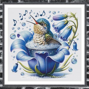 May include: A framed print featuring a hummingbird bathing in a blue flower. The bird has blue and green feathers, with a long red beak. Bubbles and musical notes surround the bird. The artwork is signed "Created by Lanna Crosswell."