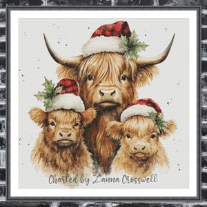 May include: Watercolor painting of three Highland cows wearing Santa hats with holly accents. The cows have long, shaggy brown fur. The text "Charted by Zanna Crosswell" is at the bottom. The artwork is framed.
