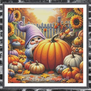 以下が含まれることがあります： 秋をテーマにした額入りのクロスステッチ。紫色の帽子と青い衣装を着たノームが、カボチャ、ヒマワリ、紅葉に囲まれています。「Charted by Laura Crosswell」の文字が見えます。