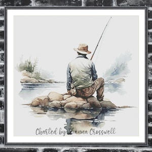 May include: Watercolor print of a person fishing, seated on rocks in a serene lake. The person wears a hat, jacket, and pants, holding a fishing rod. The artwork is framed and features the text "Charted by Joanna Crosswell".