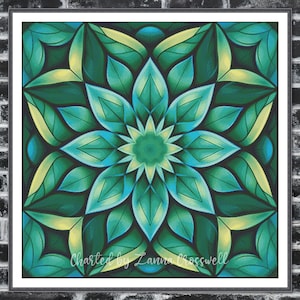 May include: A framed, square artwork with a symmetrical floral design in shades of green and teal, with yellow highlights. The text "Charted by Lanna Crosswell" is at the bottom. The artwork is displayed against a dark brick wall.