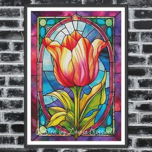 Può includere: Arte vetrata incorniciata con un tulipano. L'opera presenta un tulipano rosso, arancione e giallo con foglie verdi e uno sfondo blu. La cornice è nera e il testo "Created by Zanna Crosswell" è visibile.