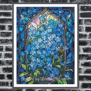 Può includere: Opera d'arte in vetrata incorniciata con fiori blu non ti scordar di me. L'opera è ambientata su uno sfondo di vetro blu e verde, con una cornice nera. Il testo "Chasted by Zanna Crosswell" è visibile in basso.