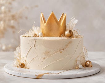 May include: A round cake with smooth off-white frosting featuring textured brush strokes and gold dust accents. The top is decorated with a large gold crown, translucent white petal-like garnishes, and various sizes of gold and white spheres.