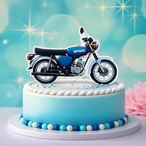 Könnte beinhalten: Ein blau-weißer Kuchen, verziert mit einem Motorrad-Kuchendekor. Der Kuchen hat ein hellblaues Ombre-Design, einen weißen Seilrand und blaue und weiße Perlenakzente. Auf der Seite befindet sich eine rosa Blume.