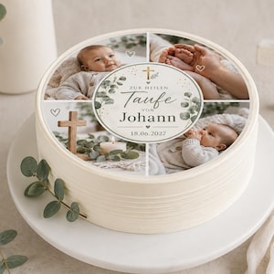 Op de afbeelding: Een ronde witte taart met een fotocollage bovenop met een baby, handen en een houten kruis. Het centrale ronde label toont de tekst Zur Heilen Taufe von Johann 18.06.2027, versierd met groene eucalyptusbladeren en een klein gouden kruis.