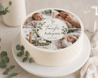 May include: A round white cake topped with a photo collage featuring a baby, hands, and a wooden cross. The center circular label displays the text Zur Heilen Taufe von Johann 18.06.2027, decorated with green eucalyptus leaves and a small gold cross.