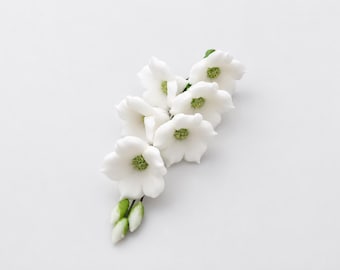 May include: A decorative floral spray featuring multiple white, five-petaled blossoms with textured, light green centers. The arrangement includes several small, closed white flower buds at the base, all attached to thin, dark green stems.