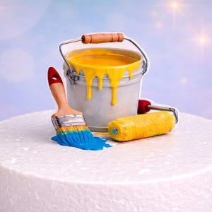 Può includere: Un secchiello di vernice in miniatura pieno di vernice gialla, che gocciola lungo il lato. Un pennello con vernice blu e un rullo di vernice giallo sono accanto al secchio. Su una superficie bianca e rotonda.