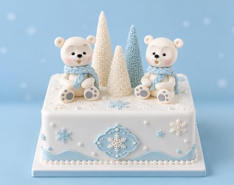 May include: A square white cake decorated with two fondant polar bears wearing light blue scarves, three textured cone-shaped trees in white and blue, and white fondant snowflakes. The base features a light blue wavy border and pearl accents.
