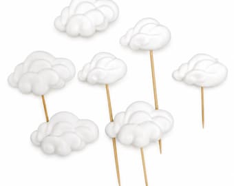 May include: A collection of seven white cloud-shaped toppers, each featuring a rounded, puffy design. Four of the clouds are attached to thin, pointed wooden sticks, while three clouds are shown without sticks, arranged on a plain white background.