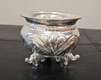 May include: A silver bowl with an ornate design and three elephant legs.