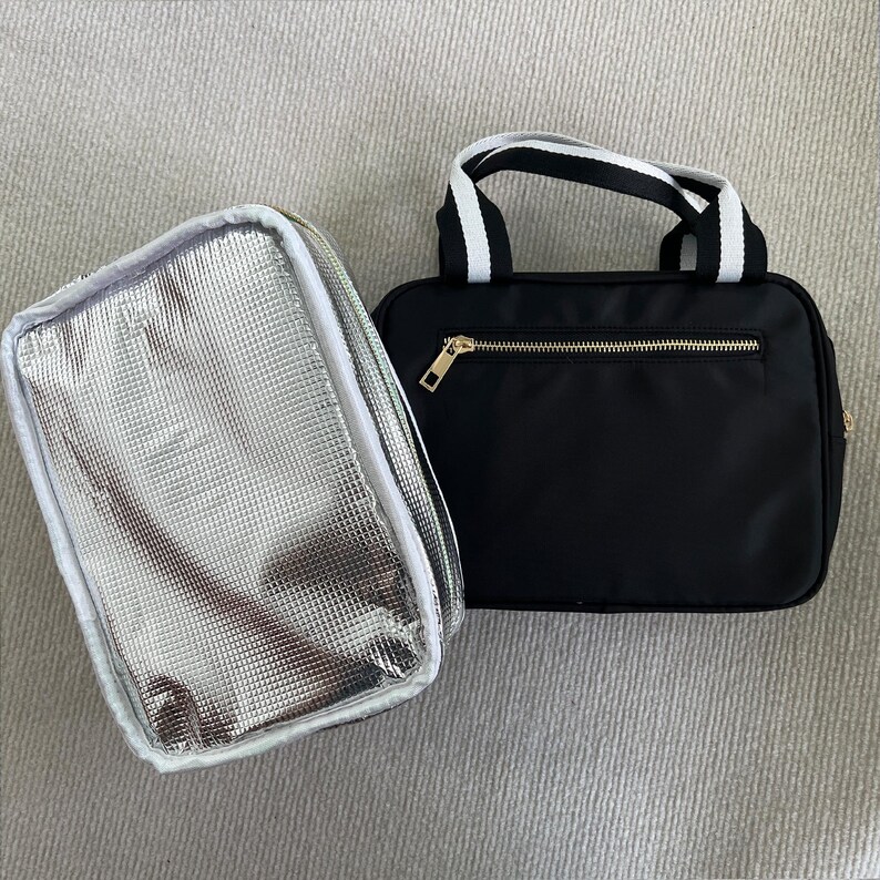 May include: Two insulated lunch bags. One is silver with a white zipper and the other is black with a gold zipper and white handles.