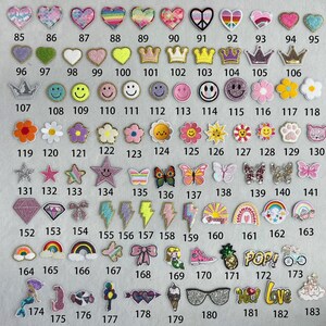 May include: A collection of 183 iron-on patches in various colors, shapes, and designs. The patches feature hearts, stars, crowns, butterflies, rainbows, and more.