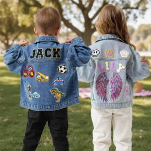May include: Two children wearing denim jackets with patches. One jacket has "JACK" on the back with patches of a tractor, crane, soccer ball, police car, and dinosaur. The other jacket has "LILY" with patches of wings, a crown, a smiley face, and a cloud.