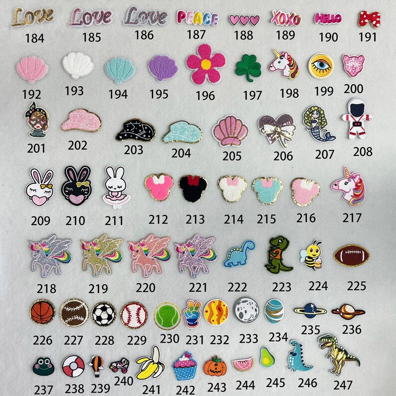 May include: A collection of 47 iron-on patches featuring various designs, including animals, hearts, words, and sports equipment. The patches are arranged in rows and numbered from 184 to 247.