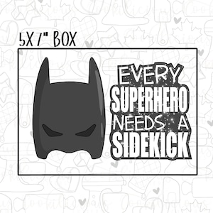 May include: A black and white image of a superhero mask with the text "EVERY SUPERHERO NEEDS A SIDEKICK" in a glittery font. The image is labeled "5x7" BOX.