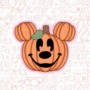 Puede incluir: Un cortador de galletas con forma de calabaza con una cara de Mickey Mouse. La calabaza es naranja y la cara es negra. El cortador de galletas tiene una hoja verde en la parte superior.