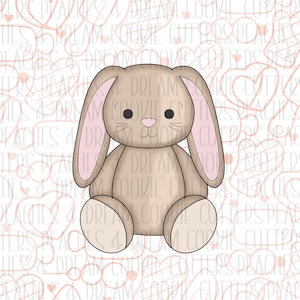 Puede incluir: Un conejito de peluche marrón con orejas rosas y una cara blanca. El conejito está sentado con las piernas cruzadas y tiene una expresión dulce.